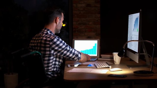 Smiling man talking by mobile phone in his home office