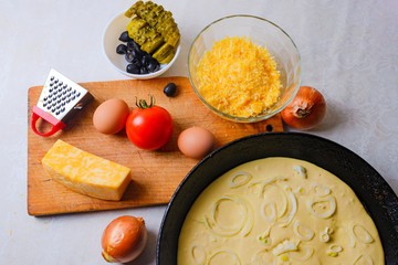 The process of cooking pizza. The view from the top. Pizza ingredients on the table with semi-finished products. Dough, tomato, eggs, cheese, olives, pickled cucumber