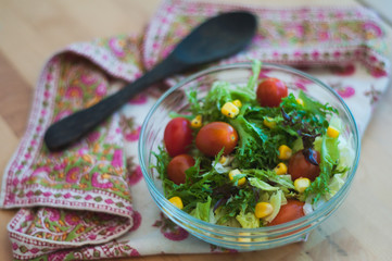 A fresh and healthy salad made with fruits and vegetables on a wooden table.