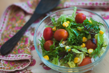 A fresh and healthy salad made with fruits and vegetables on a wooden table.