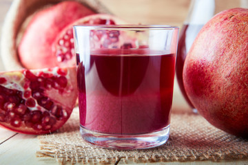 Fresh pomegranate juice in a glass on wooden background