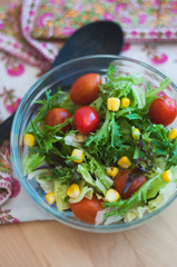A fresh and healthy salad made with fruits and vegetables on a wooden table.