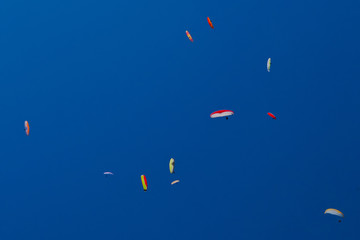 A lot of paragliders in the blue sky form whimsical patterns