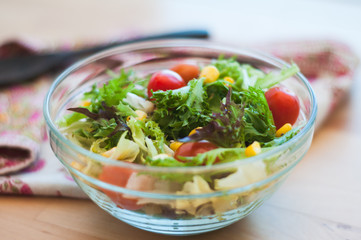 A fresh and healthy salad made with fruits and vegetables on a wooden table.