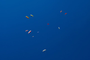 A lot of paragliders in the blue sky form whimsical patterns