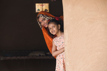 Happy mother and daughter peeking from rural house