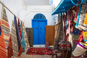 Traditional Tunesian carpets hanging on blue walls in resort town Sidi Bou Said. Tunisia, North Africa.
