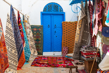 Traditional Tunesian carpets hanging on blue walls in resort town Sidi Bou Said. Tunisia, North Africa.