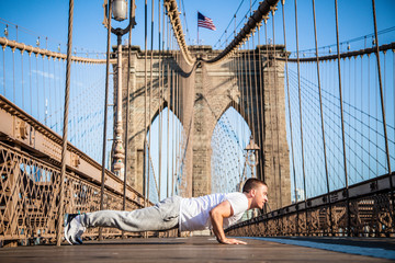 Young athlete doing pushups on Brooklyn Bridge in New York City