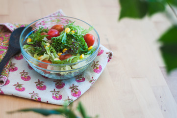 A fresh and healthy salad made with fruits and vegetables on a wooden table.