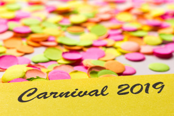 Carnaval party background concept. Space for text, copyspace. Carnival 2019. Colorful confetti spread over table. Warm colors.