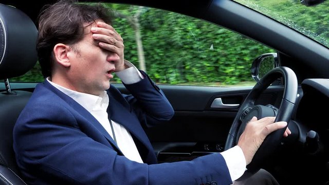 Man driving car not feeling well over stressed because of too much work