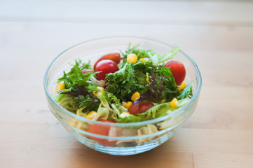 A fresh and healthy salad made with fruits and vegetables on a wooden table.