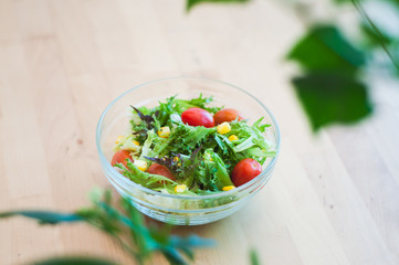 A fresh and healthy salad made with fruits and vegetables on a wooden table.