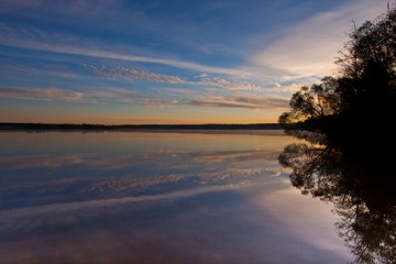 Reflections on the contrary, Dawn over the quiet water surface of the lake