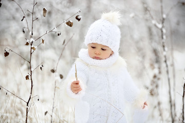 Cute little toddler boy and his older brothers, playing outdoors with snow on a winter day