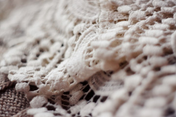 delicate white lace is laid on a woolen beige fabric