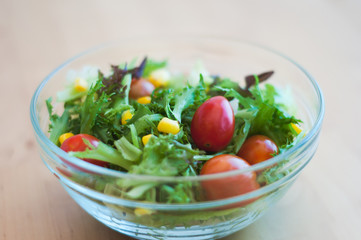 A fresh and healthy salad made with fruits and vegetables on a wooden table.