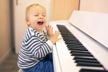 Sweet positive toddler child playing piano. Early music education for little kids.