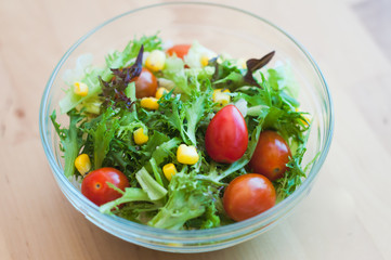 A fresh and healthy salad made with fruits and vegetables on a wooden table.