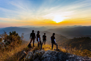 Obraz premium Silhouette of man hold up hands on the peak of mountain,success concept