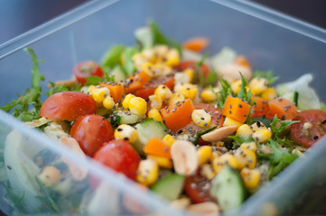 Close up of fresh and healthy salad made with fruits and vegetables in a container.
