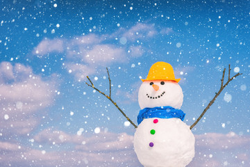 Cute smiling snowman against blue sky background with falling snowflakes, happy winter concept