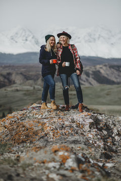 Two hipster traveler girls standing and admiring beautiful view of mountains