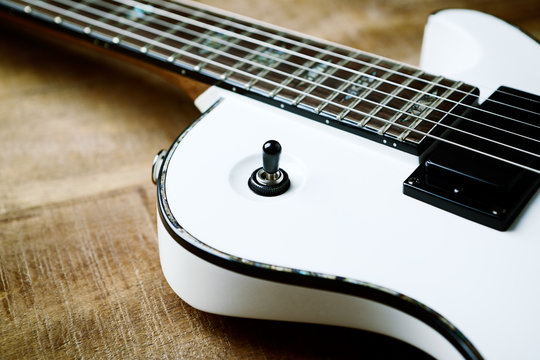 Body and fretboard of modern electric guitar on rustic wooden background. 