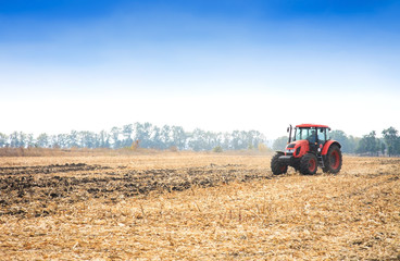 Modern red tractor working on the field