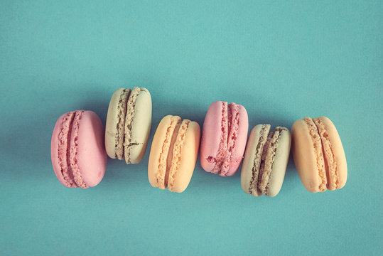 Traditional french macaroons with raspberries, mint on the blue background with copy space