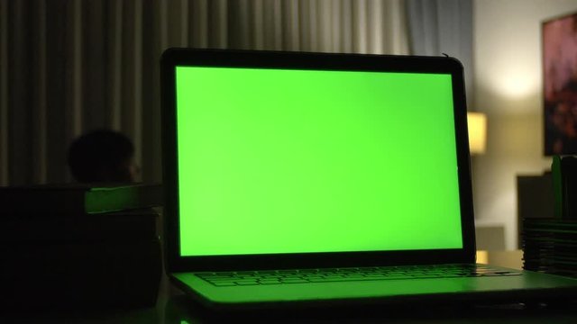 Laptop with green screen. Dark home office . Dolly shot of Perfect to put your own image or video. 