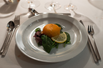 Salmon starter with salad, lemon, on restaurant table