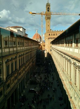 Florence, Italy - April 1 2018: View of the crowded courtyard from the windows of Uffizi Gallery with a construction crane, the Cathedral dome and clock tower of Palazzo Vecchio in the background