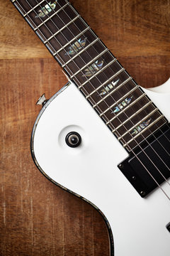 Body and fretboard of modern electric guitar on rustic wooden background. Top view. Copy space. 