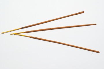 three Indian incense sticks on a solid light background