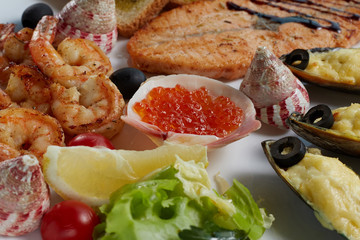 Fototapeta na wymiar seafood of salmon, caviar, mussels, fried shrimp, cherry tomatoes, lemon, lettuce and olives