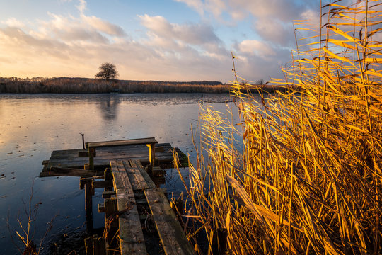 Autumn landscape with a wooden footbridge and the setting sun at the lake near Konstancin-Jeziorna, Masovia, Poland