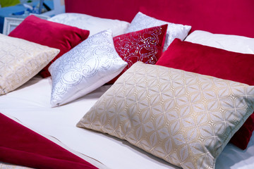 Decorative pillows from velvet and brocade on the bed in the bedroom.