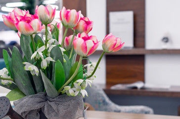 Pink tulips in metal flowerpot on a wooden table.