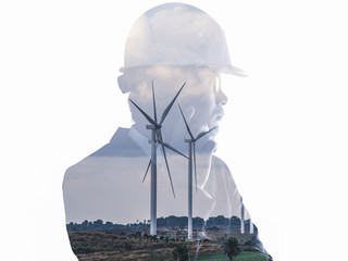 The double exposure image of the engineer standing back during sunrise overlay with wind turbine...