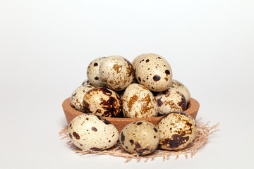 Closeup Easter small fresh textural quail eggs in round wooden bowl with textile isolated on white background. Concept traditional treat Orthodox Christian spring Church holiday. Free space, copyspace