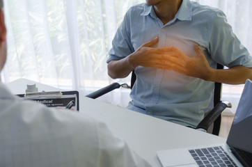 young man hands on his chest suffering from heart attack meet doctor writing prescription on clipboard with laptop on desk in hospital, office syndrome, health care, medical, heart disease concept