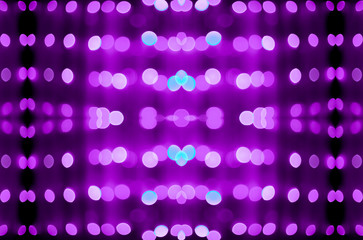 Abstract symmetric glitter defocused purple lights bokeh texture on black background