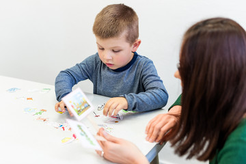 Young boy in speech therapy office. Preschooler exercising correct pronunciation with speech therapist. Child Occupational Therapy Session. - obrazy, fototapety, plakaty