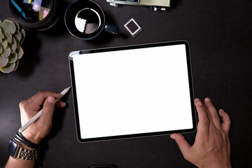 Graphic designer working with digital drawing tablet on dark office desk