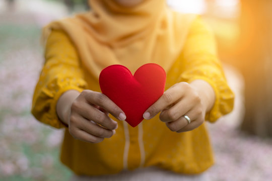 hand of young muslim woman hold red heart  in her hand, love and care concept,  international world peace concept