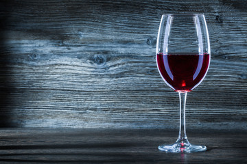 glass with red wine on wintage wood close up view.