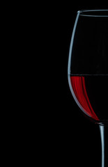 very close up view on wineglass with red wine on black background.
