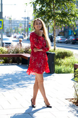 Sexy blonde model posing on th street in red summer dress